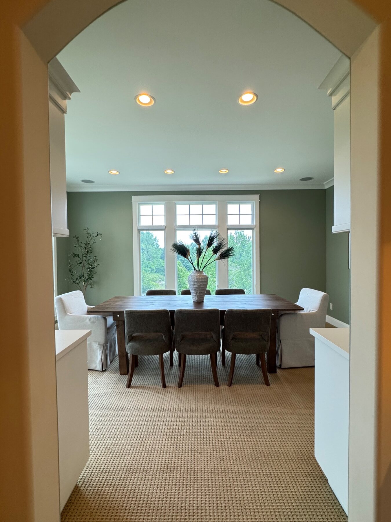 Dining room staged with a long wood table framed by an architectural arch